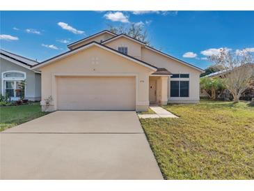 Tan two-story house with a double-car garage and a small front yard at 1448 Brook Hollow Dr, Orlando, FL 32824