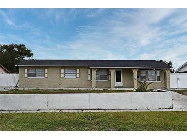 Ranch style home with a yellow brick exterior, dark roof, and a low concrete wall in the front yard at 2090 Ashland Blvd, Orlando, FL 32808