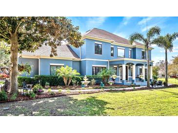 Stunning two-story home with a blue exterior, lush landscaping, fountain, and inviting front porch at 3943 W Campbell Rd, Lakeland, FL 33810