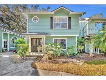 Two-story light green house with dark brown doors and landscaping at 5978 Braemar Pl # 108, Orlando, FL 32822