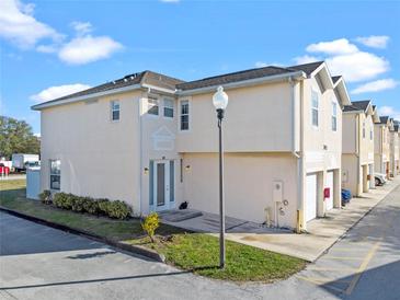 Tan two-story townhome with white door, attached garage, and landscaping at 7415 Lago De Oro # 2, Orlando, FL 32822