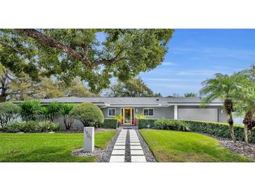 Charming single-story home with mature landscaping and a striking yellow door at 1901 Lake Sue Dr, Orlando, FL 32803