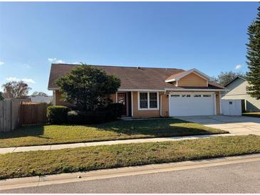 Tan house with a two-car garage and a fenced backyard at 1938 Gamboge Dr, Orlando, FL 32822