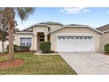 Tan one-story house with a two-car garage and well-manicured lawn at 2220 Wyndham Palms Way, Kissimmee, FL 34747