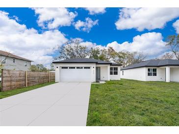 Newly constructed home with a white exterior, two-car garage, and a well-manicured lawn at 2905 Palmetto Ave, Sanford, FL 32773