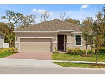 Charming single-Gathering home featuring a brick driveway, two-car garage, and well-manicured lawn at 1123 Happy Forest Loop, Deland, FL 32720