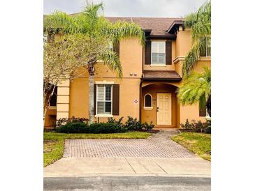 Tan two-story townhome with dark brown shutters and a paved driveway at 3428 Calabria Ave, Davenport, FL 33897