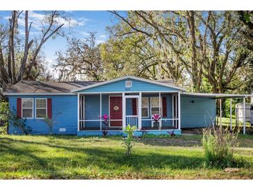 Charming light blue house with red door and screened porch at 4935 Sand Mountain Loop Rd, Auburndale, FL 33823