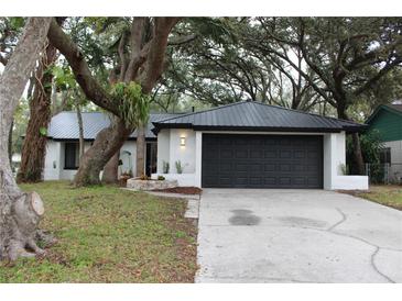 Updated home exterior boasts a modern black roof and garage door, plus a landscaped front yard at 1461 Lancelot, Casselberry, FL 32707