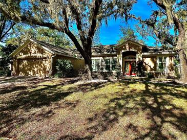 Single-story home with a red door, two-car garage, and mature landscaping at 1701 Sparkling Water Cir, Ocoee, FL 34761