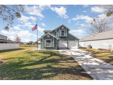 Two-story house with a green exterior, attached garage, and a well-maintained lawn at 2210 Kentucky Derby Dr, Orlando, FL 32825