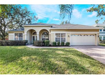 One-story house with arched entryway, beige exterior, and well-manicured lawn at 268 Heatherbrooke Cir, Oviedo, FL 32765