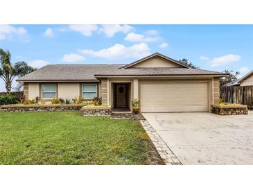 Tan house with a brown roof, stone accents, and a two-car garage at 2700 Dorado Ct, Apopka, FL 32703