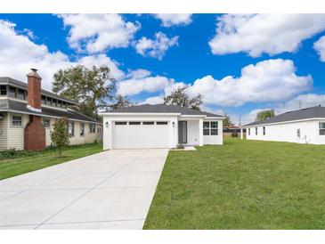 Newly constructed home with a white exterior, a two-car garage, and a well-manicured lawn at 2712 Alamo Dr, Orlando, FL 32805