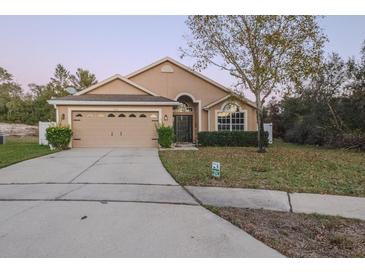 Tan house with a two-car garage and a landscaped yard at 3202 Alling, Deltona, FL 32725