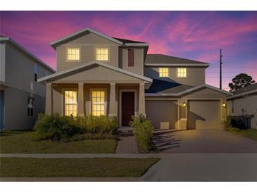 Two-story house with beige siding, a two-car garage, and landscaping at 3975 Great Smokey Way, Apopka, FL 32712