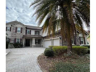 Two-story house with stone accents, three-car garage, and palm tree at 15041 Gaulberry Run, Winter Garden, FL 34787