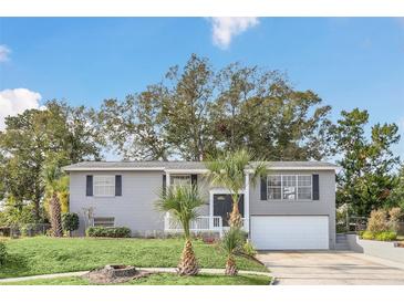 Gray house with white garage door, landscaping, and palm trees at 4862 Indialantic Dr, Orlando, FL 32808