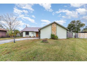 Light green house with brown metal roof, stone accents, and a landscaped yard at 628 Twin Oaks Cir, Daytona Beach, FL 32117