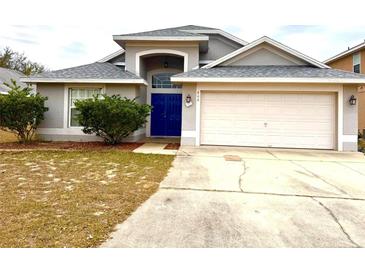 Two-story house with gray siding, attached garage, and blue front door at 800 Woodlark Dr, Davenport, FL 33897