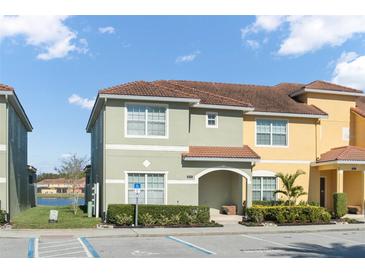 Two-story townhome with light green and yellow exterior, landscaping, and parking at 8925 Candy Palm Rd, Kissimmee, FL 34747