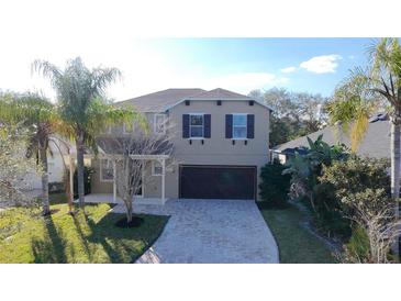 Two-story home featuring a neutral color scheme, well-manicured lawn, and a beautiful paver driveway at 13124 Oulton Cir, Orlando, FL 32832