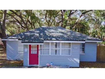 Charming light blue house with red door, surrounded by lush trees at 1338 S Elliott St, Sanford, FL 32771