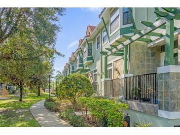 Row of townhouses with green exterior, landscaped grounds, and walkways at 14531 Damai Ln, Orlando, FL 32821