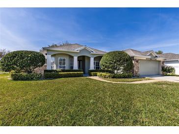 Single-story house with a two-car garage, manicured lawn and landscaping at 346 Hickory Springs Ct, Debary, FL 32713