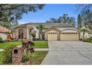 Brick house with three-car garage, manicured lawn, and mature trees at 3838 Gatlin Place Cir, Orlando, FL 32812