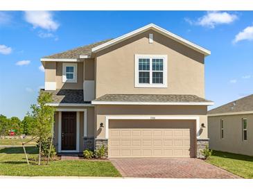 Two-story home featuring a two-car garage, neutral stucco, brick paver driveway and landscaped front yard at 7100 Cherry Pasture Rd, Groveland, FL 34736