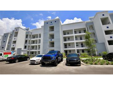 Apartment building exterior with parking and landscaping at 3151 Paradox Cir # 405, Kissimmee, FL 34746
