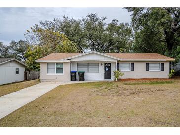 Tan house with a brown roof, driveway, and small front yard at 5511 Indian Hill Rd, Orlando, FL 32808