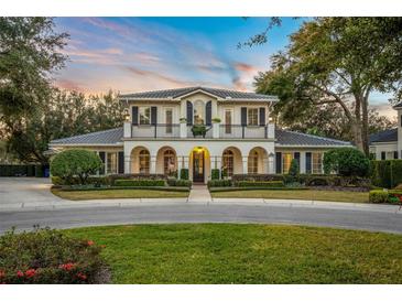 Two-story house with a balcony, arched entryway, and manicured lawn at 1000 Via Tuscany Oaks Way, Winter Park, FL 32789