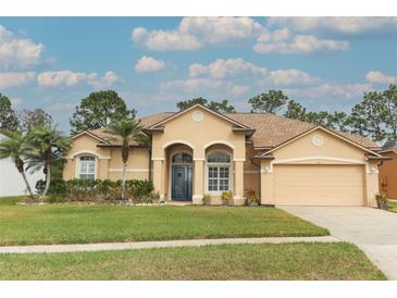 Tan one-story house with blue door, palm trees, and a two-car garage at 11537 Blackmoor Dr, Orlando, FL 32837