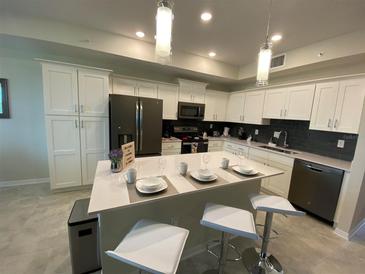 Modern kitchen with white cabinets, stainless steel appliances, and an island at 3151 Paradox Cir # 103, Kissimmee, FL 34746