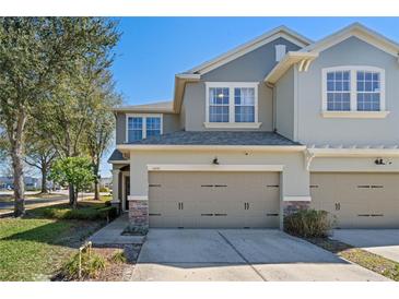 Two-story townhome with neutral siding, two-car garage, and landscaping at 5441 Leighton Ln, Oviedo, FL 32765