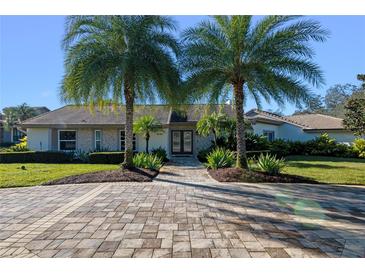 Ranch style home with paver driveway, landscaping, and two palm trees at 5737 Masters Blvd, Orlando, FL 32819