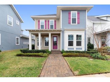 Two-story house with taupe and blue siding, pink shutters, and a covered porch at 8226 Nemours Pkwy, Orlando, FL 32827