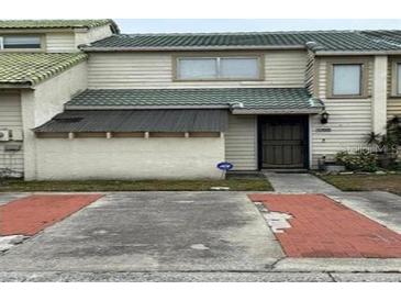 Two-story townhome with light-colored siding and a green roof at 1350 Winter Green Way, Winter Garden, FL 34787