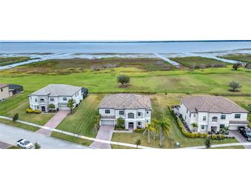 Aerial view of three homes with lake access and lush landscaping at 1551 Gateway Ln, Kissimmee, FL 34746