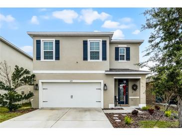 Two-story house with neutral siding, dark shutters, and a white garage door at 229 Gina Ln, Davenport, FL 33837