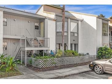 Two-story condo building with gray siding, stairs, and a landscaped area at 2536 Lemon Tree Ln, Orlando, FL 32839