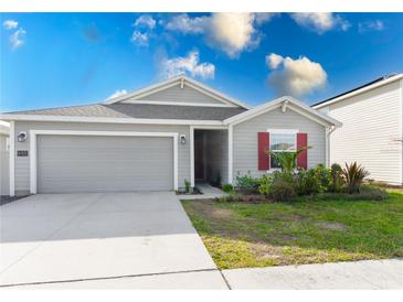 Gray house with red shutters, two-car garage, and landscaped lawn at 445 N Andrea Cir, Haines City, FL 33844