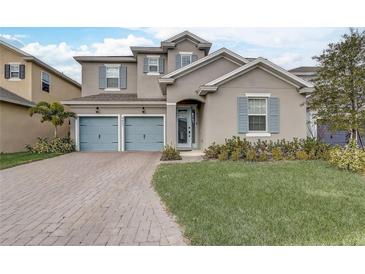 Two-story house with light taupe exterior, blue shutters, and a paved driveway at 4457 Lions Gate Ave, Clermont, FL 34711