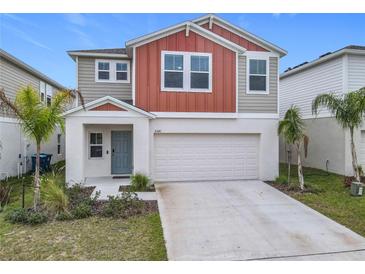 Two-story house with gray and burnt orange siding, two-car garage, and landscaping at 5381 Maddie Dr, Haines City, FL 33844