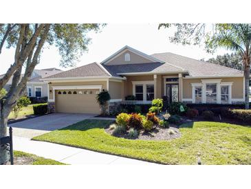 Single-story home with a beige facade, attached garage, and well-manicured landscaping at 250 Bayou Bend Rd, Groveland, FL 34736
