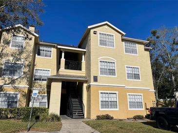 Two-story condo building with multiple units, landscaping, and parking at 2558 Robert Trent Jones Dr # 1427, Orlando, FL 32835