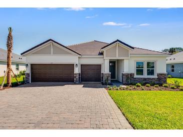 Charming single-story home featuring a two-car garage, paver driveway, and well-manicured lawn on a sunny day at 2987 Arranmore Dr, Ormond Beach, FL 32174