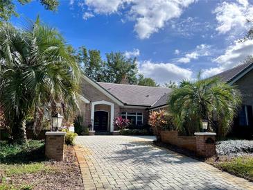Brick home with a paver driveway and lush landscaping at 5001 Latrobe Dr, Windermere, FL 34786